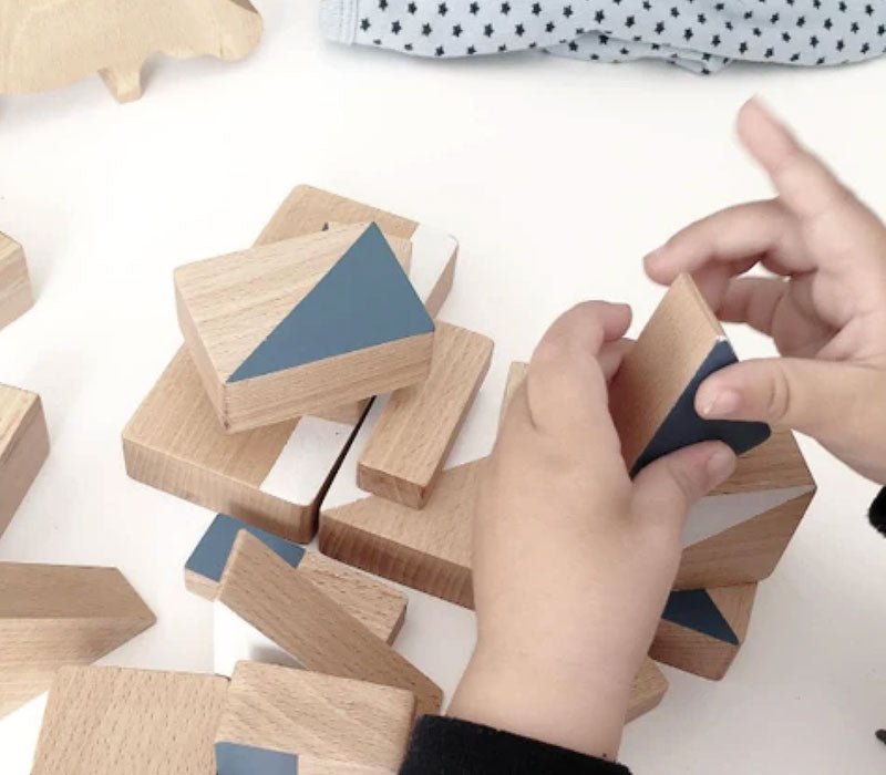 Manos de niño jugando con bloque de construcción de madera