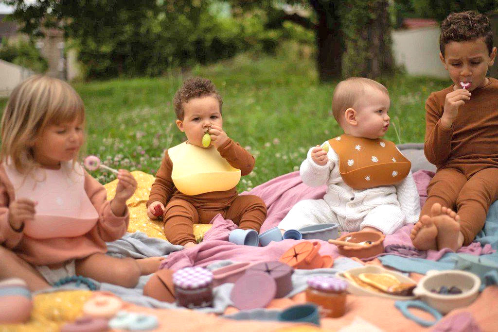 bebés sentados en una gran alfombra al aire libre