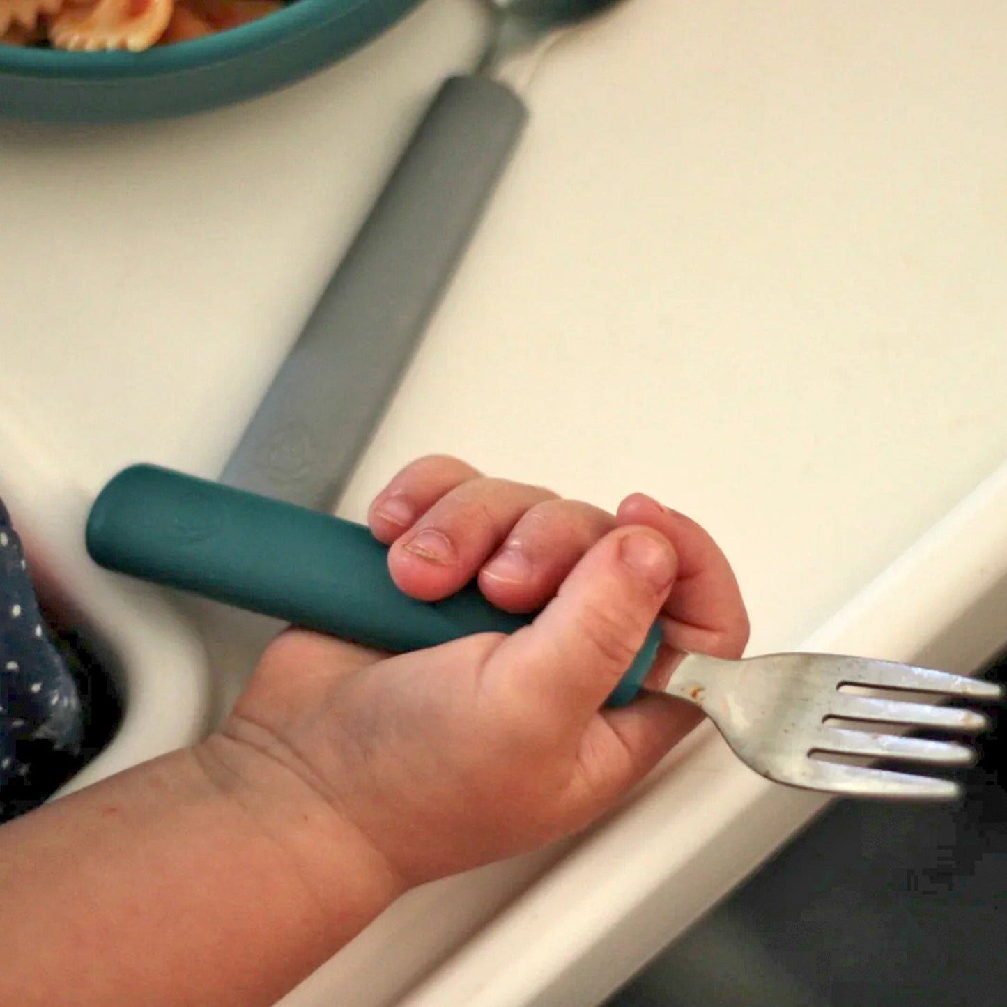 Mano de bebe con cubierto azul | Chin Pum