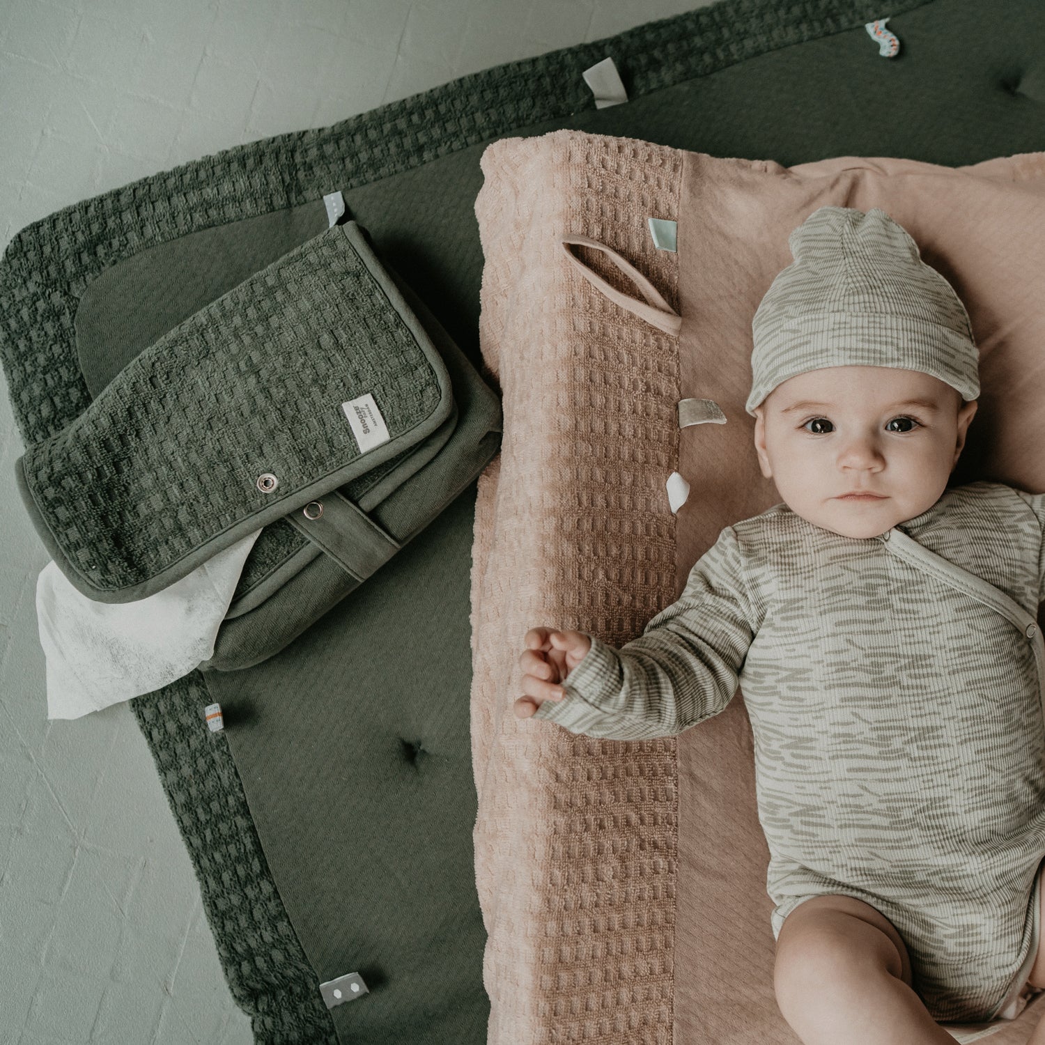 Bebé tumbado con portatoallitas verde SnoozBABY | ChinPum