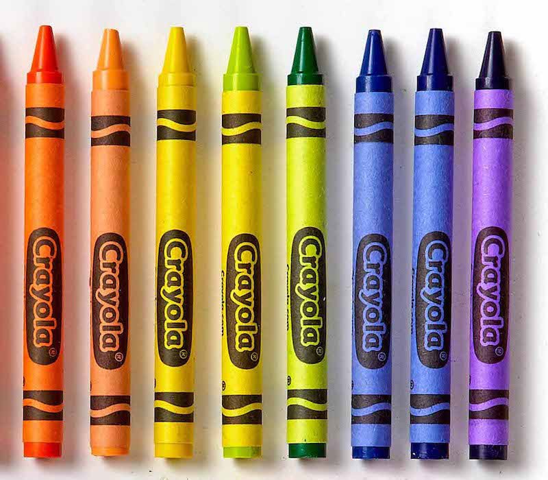 8 lapices de cera marca crayola de diferentes colores colocados paralelamente, en vertical, y uno junto al otro.