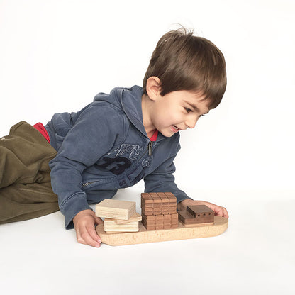 Niño feliz jugando con un barquito de bloques de madera 