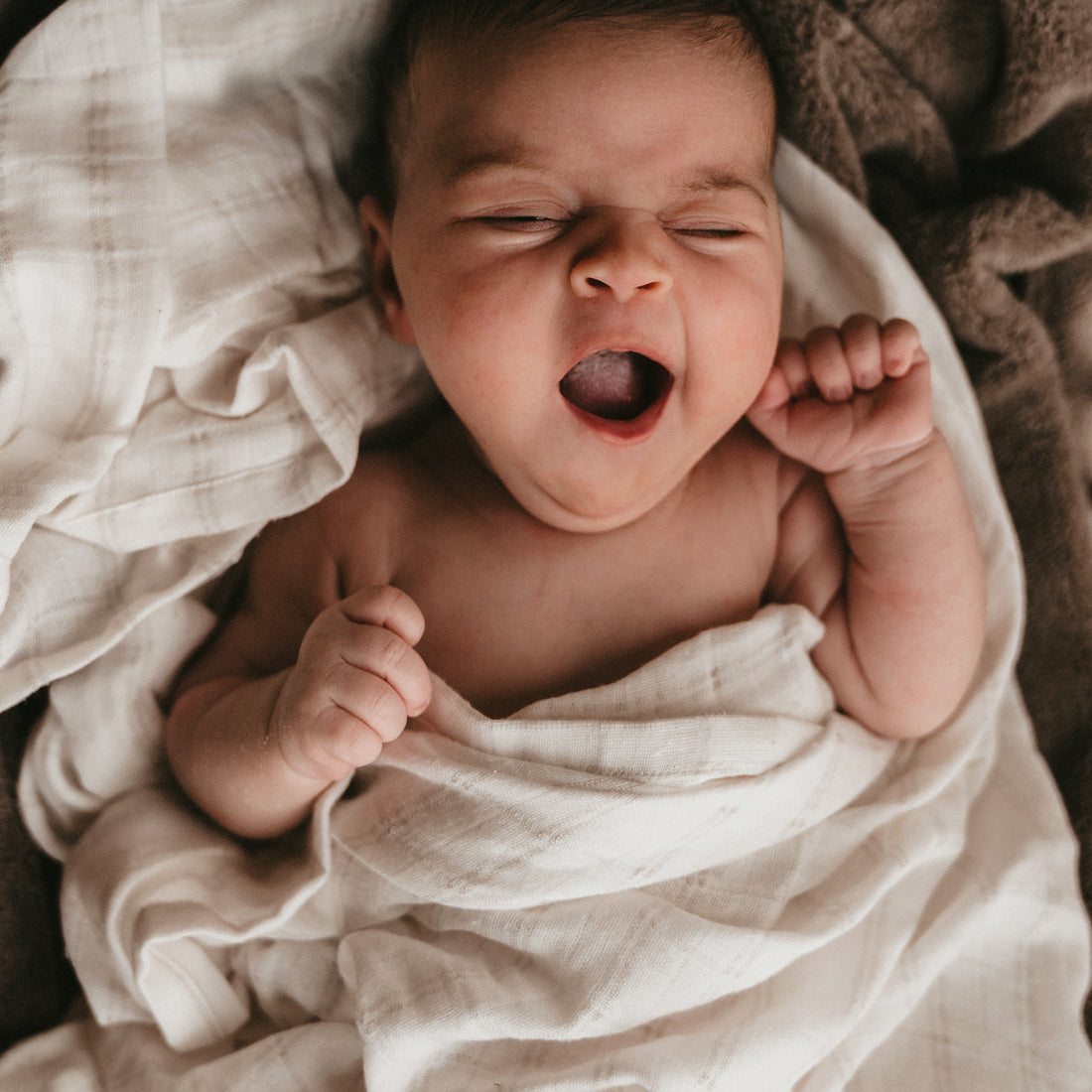 Bebé bostezando rodeado con muselina blanca | Chin Pum