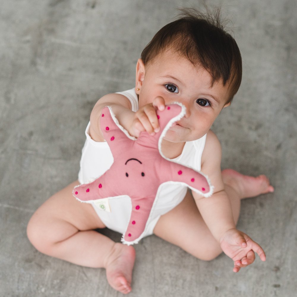 Bebé de 9 meses muestra un sonajero con forma de estrela de mar de tela