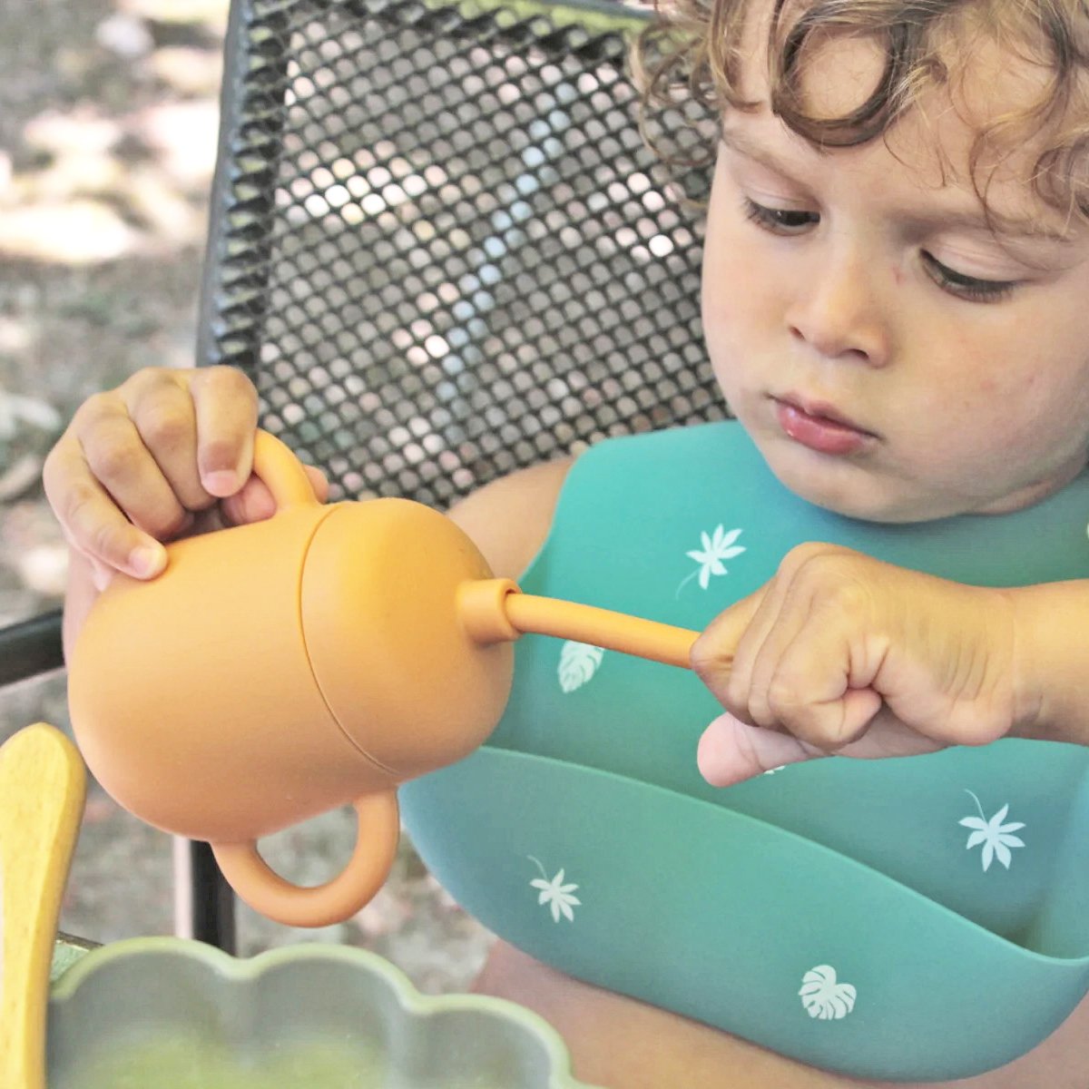 Bebé de 18 meses manipulando un vaso 3 en 1 de silicona de color amarillo