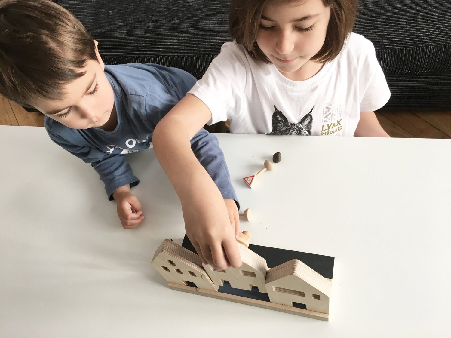 Dos niños jugando con unas casitas de juguete hechas de madera