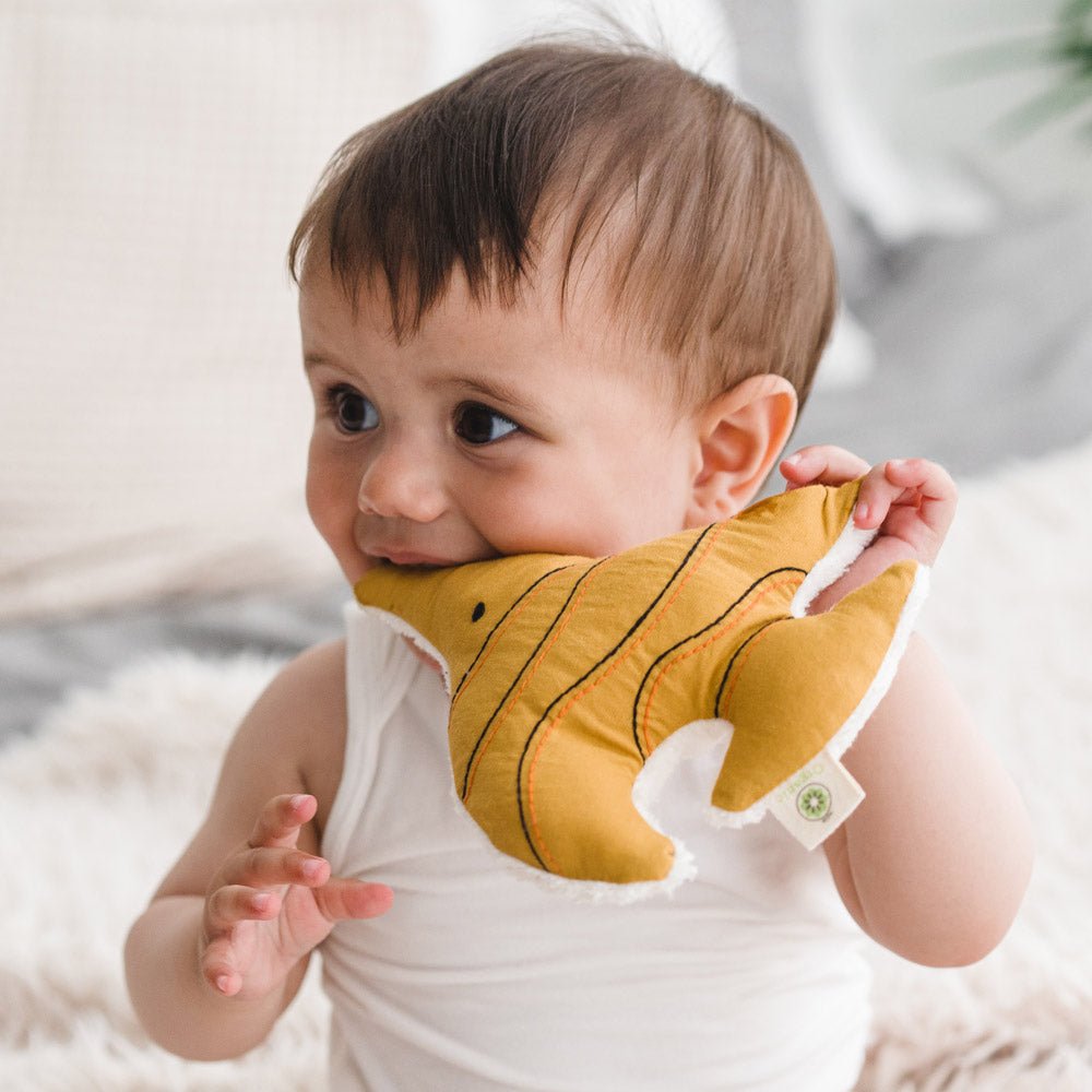 Bebe jugando con un sonajero amarillo de tela con forma de pez