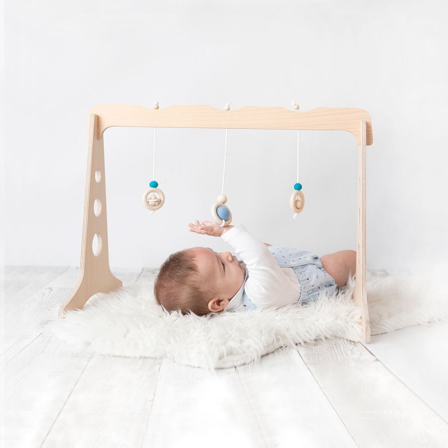Bebé jugando con un gimnasio para bebés de madera de 3 colgantes de la marca ChinPum