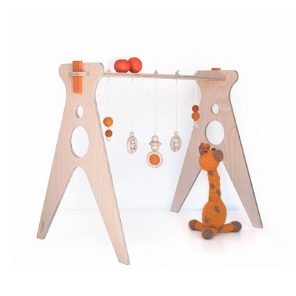 gimnasio para bebé de madera con complementos en color naranja