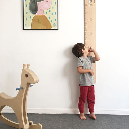 Niño midiéndose en un medidor infantil de pared de madera en su habitación