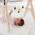 Bebé tumbado jugando con un gimnasio de madera para bebés de 5 colgantes de la marca ChinPum