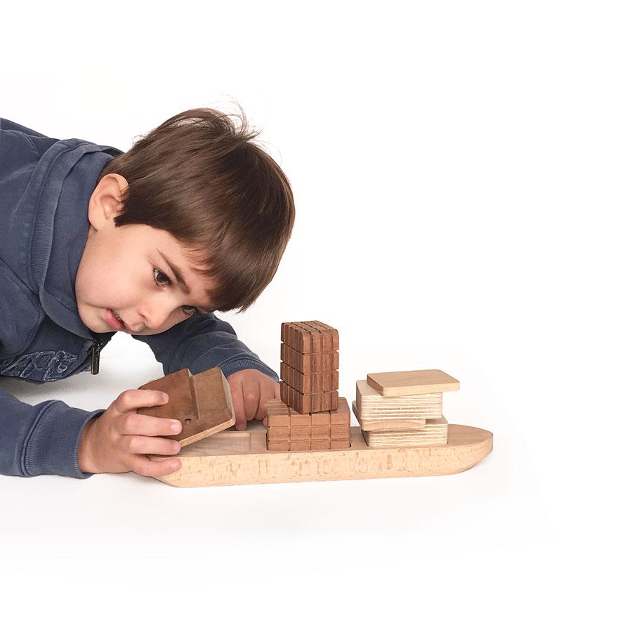 Niño jugando con un barco de madera hecho a mano | ChinPum