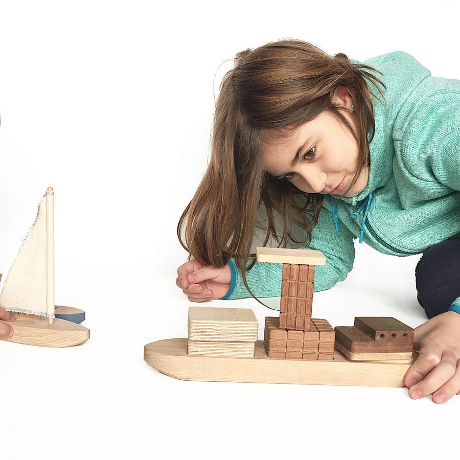 Niña jugando con un barco de madera 
