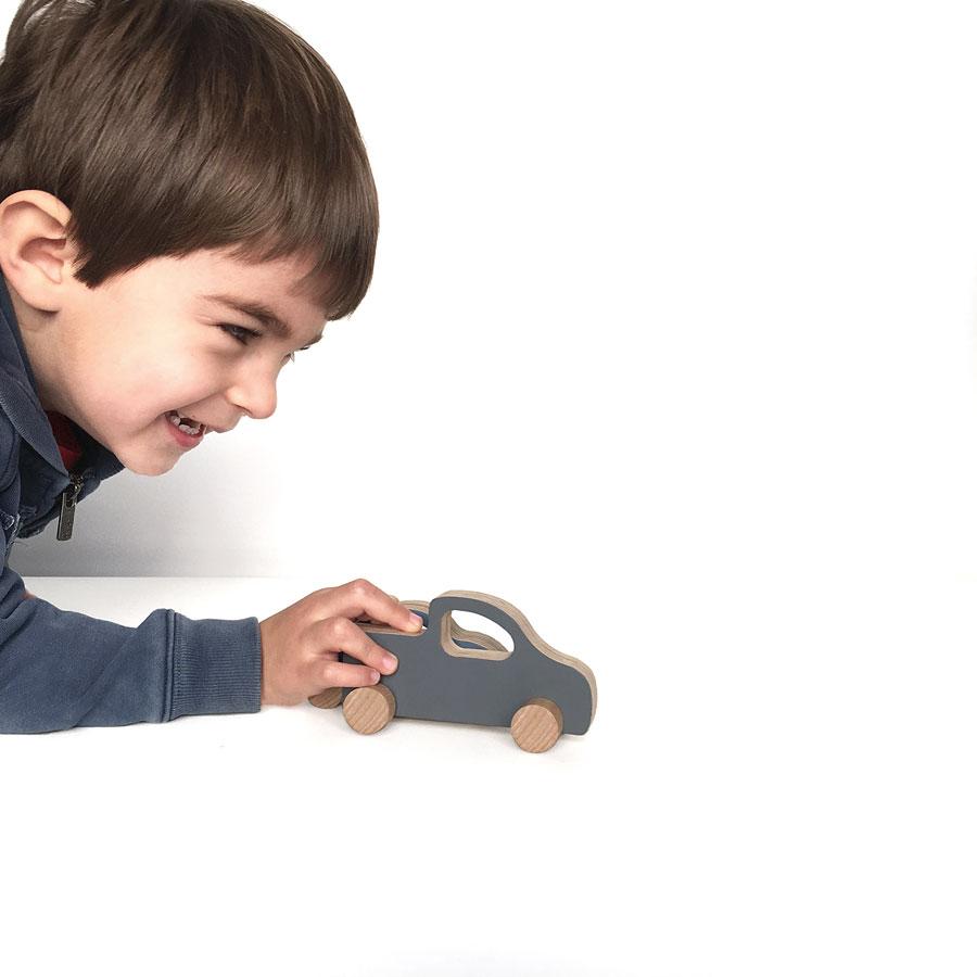 niño jugando con coche pick up de juguete hecho en madera